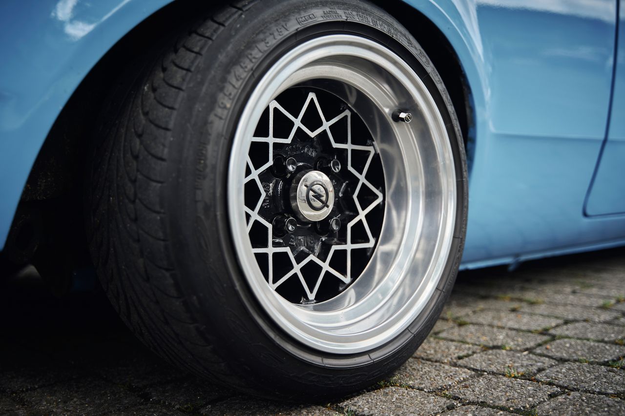 Detailed view of a stylish alloy wheel on a classic blue car, showcasing design and craftsmanship.