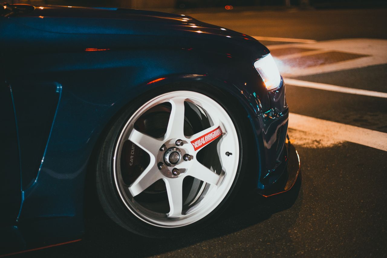 Detailed view of a dark blue modified car wheel with lights on at night.